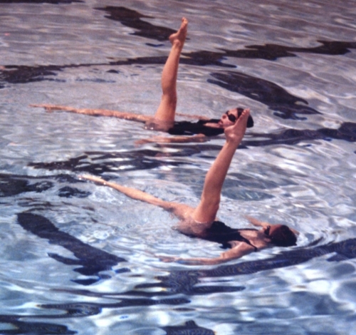 two synchronized swimmers performing in a pool